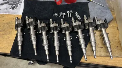 Eight injectors staged with bolts — cleaned and ready to go back in.