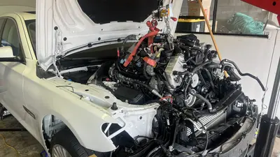 Engine nearly in the bay — front dress and hanging coolant hoses.
