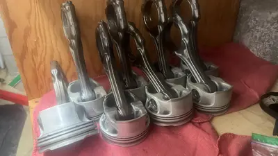 Eight pistons with rods staged clean — ready to go back in.