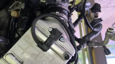 Boost sensor on the right intercooler — two Home Depot replacement bolts; OEM BMW bolts were about $7 each and went missing in teardown.