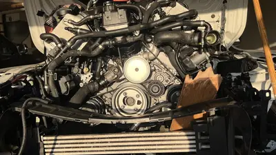 Engine back in the bay — belt, water-pump pulley, and coolant routing.