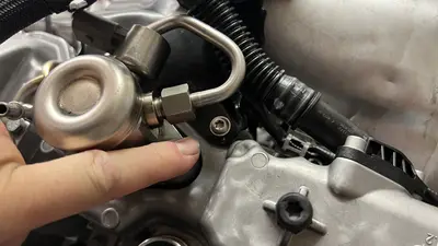 Pointing out the bolt type just above the HPFP — existing fastener, not a missing hole.