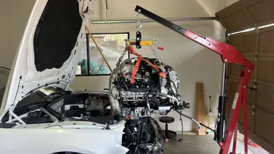 Engine on the hoist, lined up with the open bay for reinstall.