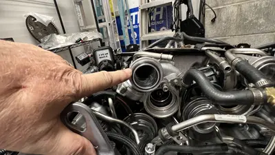 Hand at a large port — checking turbo/intake interface on the stand.