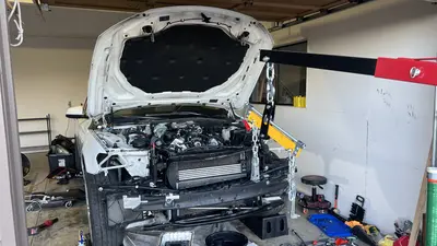 Front end stripped and hoist on: radiator/intercooler exposed, load leveler chained for the engine pull.