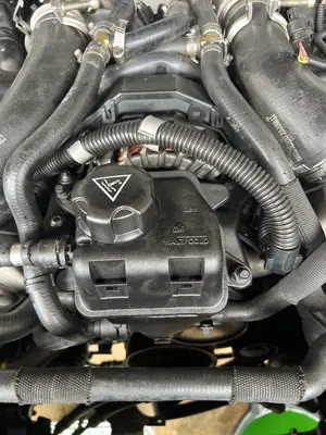 Coolant expansion tank and surrounding hoses; cooling-system work in the bay.