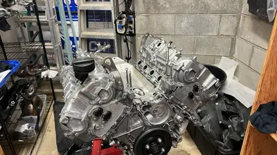 Long block nearly dressed on the stand — one bolt still missing from the cam-sensor cover.