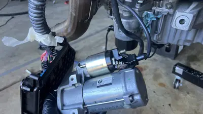 Denso starter in hand by the junction box — wiring and orientation for reinstall.