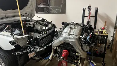 Long block on the stand in front of the empty bay — ready to go back in once the balancer bolt arrives.