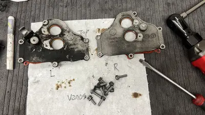 VANOS covers L vs R: left still caked in sludge, right scrubbed; bolts kept labeled.