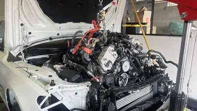Engine hanging on the hoist — front belt drive and hanging connectors.