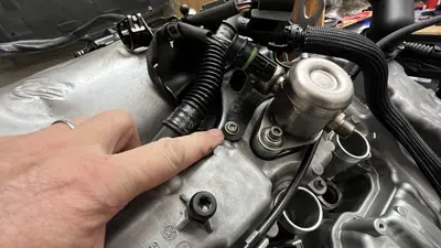 Finger on a cover fastener — still chasing the missing bolt.