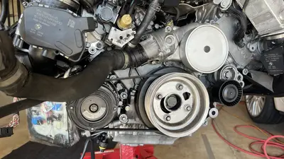 Front of the dressed long block on the stand — serpentine belt, pulleys, and coolant hose routing.